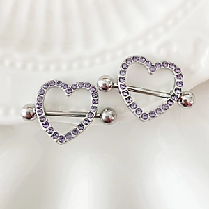 Dettaglio di piercing al capezzolo a forma di cuore con zirconi viola su piatto ceramica