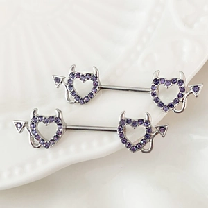 Dettaglio di piercing per capezzoli a cuore argento con cristalli viola su piatto bianco
