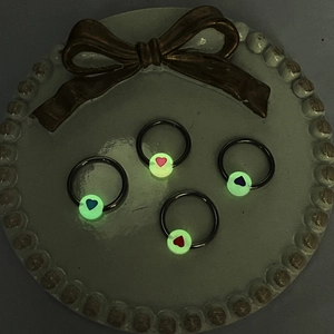 Luminous heart nipple rings set featuring glowing beads on circular metal piercings