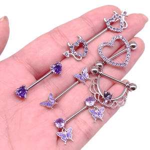 Dettaglio ravvicinato di piercing al capezzolo a cuore con zirconi viola e metallo argento