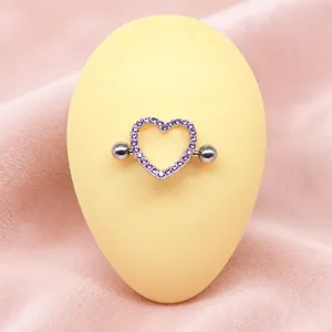 Dettaglio del piercing al capezzolo a cuore con zircone viola su modello in silicone