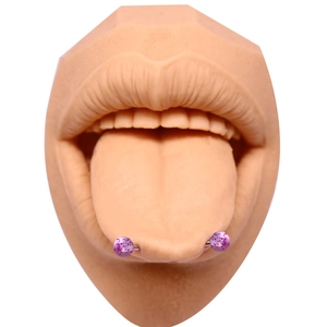 Détail de piercings de langue violets pailletés sur un modèle de bouche en silicone