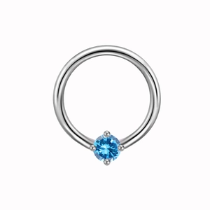 Macro detail of silver piercing hoop with a four-prong set round blue gemstone inlay