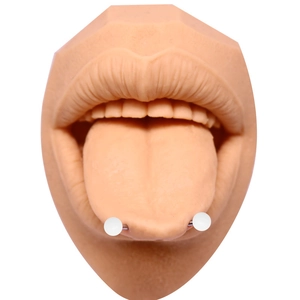 Détail d'un piercing de langue à boules blanches en acrylique sur un modèle de bouche