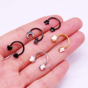 Detailed macro of five punk-style horseshoe nose rings with star and butterfly charms