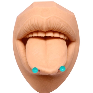 Gros plan d'un piercing de langue en acrylique turquoise exposé sur un modèle en silicone