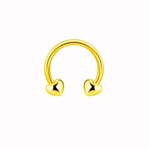 Macro detail of golden heart-shaped ends on a polished horseshoe nose ring barbell