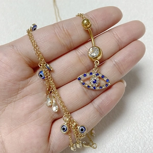 Λεπτομερής προβολή του Evil Eye piercing ομφαλού και χρυσή αλυσίδα μέσης με κρύσταλλα