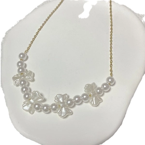 Elegant gold chain necklace featuring white pearls and delicate ribbon bow charms