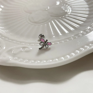 Piercing de langue libellule rose et blanc avec bille filetée sur assiette en céramique
