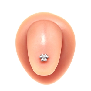 Détail d'un piercing de langue papillon argenté avec textures pointillées sur modèle