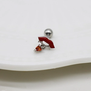 Nahaufnahme eines Piercings aus Silber mit rotem Lippen-Anhänger und orangem Herz-Zirkon