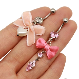 Makroansicht von Bauchnabelpiercings mit rosa Schleifen, Herzperlen und Zirkonia