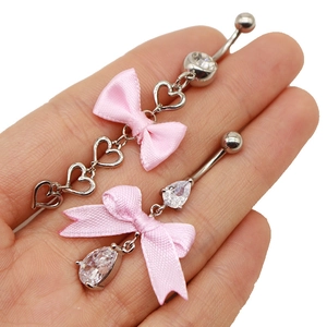 Nahaufnahme von Herz-Bauchnabelpiercings mit rosa Seidenschleifen und Zirkonia-Steinen