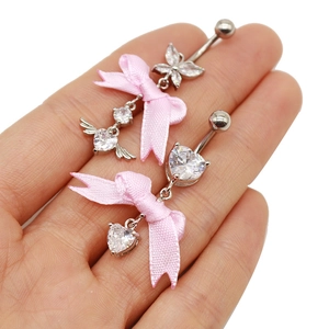 Nahaufnahme von rosa Schleifen-Bauchnabelpiercings mit Herz- und Flügelanhängern