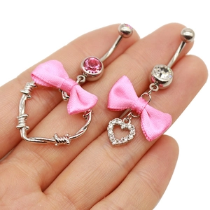 Detailansicht der Bauchnabelpiercings mit rosa Schleifen und Herzanhängern aus Zirkon