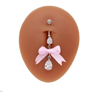 Nahaufnahme von herzförmigem Bauchnabelpiercing mit rosa Schleife auf einem Silikonmodell
