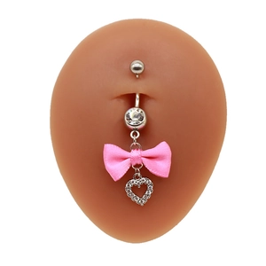 Nahaufnahme von silbernem Bauchnabelpiercing mit rosa Seidenschleife und Herzanhänger