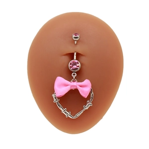 Detailansicht Bauchnabelpiercing mit rosa Schleife und Stacheldraht-Herzanhänger