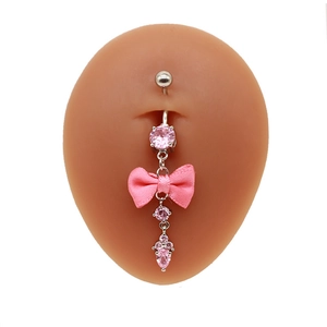 Detail eines Bauchnabelpiercings mit rosa Zirkon und Stoffschleife auf Silikonmodell