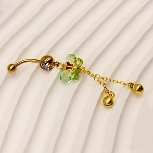 Detail of gold belly ring featuring a translucent green butterfly and bell tassels