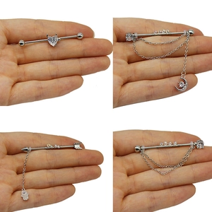 Viste dettagliate di vari piercing industriali con catene d'argento e zirconi cubici