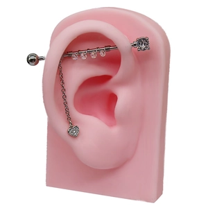 Dettaglio piercing industriale con ciondolo a cuore su modello di orecchio in silicone