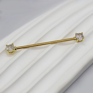 Dettaglio macro dell'orecchino barbell industriale dorato con zirconi tondi brillanti