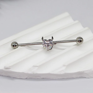 Dettaglio macro del piercing industriale argento con zircone a cuore e corna da diavolo