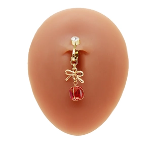 Dettaglio clip per ombelico dorata con fiocco e perla rossa, design senza foro