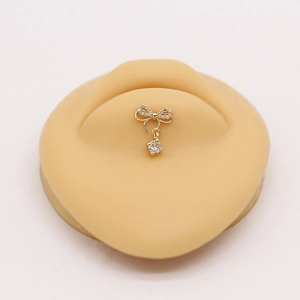 Detailed view of a gold bow labret stud with pavé zircons and a round crystal pendant