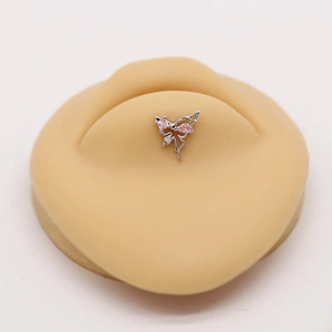 Macro view of butterfly piercing stud with pink zircon on skin-tone silicone model