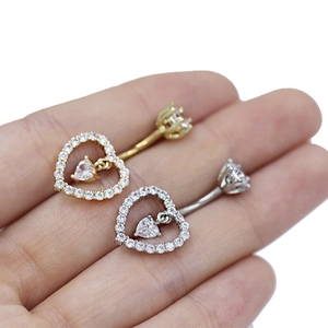 Detalle de piercings de ombligo con forma de corazón en oro y plata con circonitas