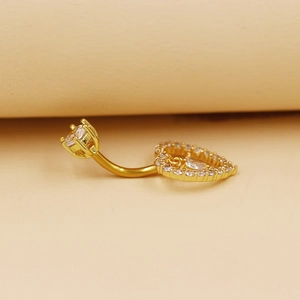 Primer plano detallado de un piercing para el ombligo dorado con corazón de circonita