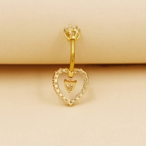 Vista detallada de un piercing de ombligo de corazón dorado con circonita sobre fondo suave