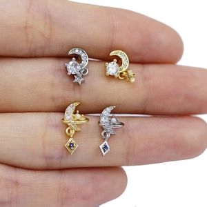 Macro detail of planet and star dangles on labret studs in gold and silver plating