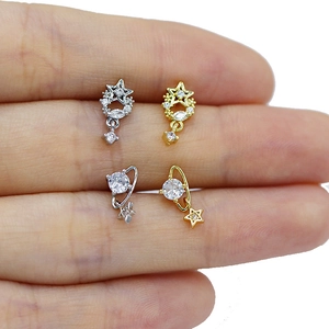 Detailed macro view of four mini zircon star and moon stud earrings on a fingertip