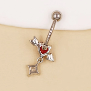 Detalle de piercing de ombligo plateado con corazón rojo y colgante de circonita