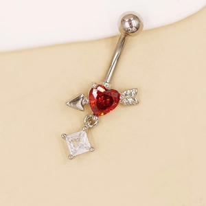 Detalle de piercing de ombligo de corazón con circonita roja y diseño de flecha