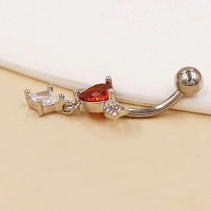 Primer plano de piercing de ombligo con circonita roja de corazón y cristal blanco
