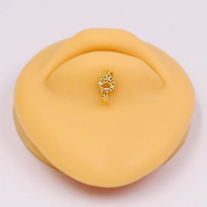 Detail of a golden star-shaped belly button ring with inlaid zircons on a silicone navel mold
