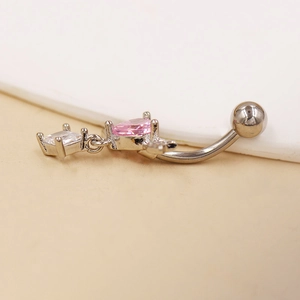 Detalle macro del piercing de ombligo con circonita corazón rosa y barra curva plata