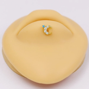 Detail of moon-shaped gold piercing jewelry with blue and white zircon on skin model