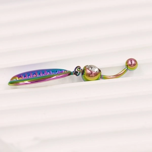 Macro-opname van regenboog navelpiercing met kristal en hanger in de vorm van een blad