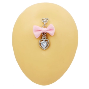 Detalle de piercing para ombligo con circonitas de corazón y un lazo de satén rosa
