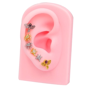 Golden and silver planet stud earrings set with purple zircon on ear mold display