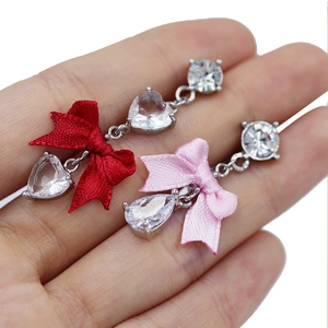 Detalle de piercings de ombligo colgantes con circonitas de corazón y lazos de colores