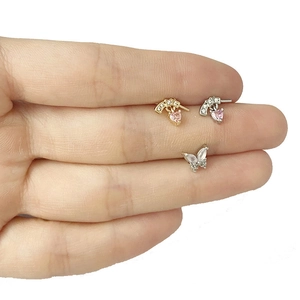 Detalle de piercings de mariposa y corazón rosa en acabados dorado y plateado