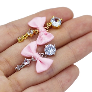 Detalle del anillo de ombligo con lazo de seda rosa y circonitas brillantes en la mano