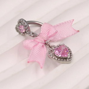 Detalle de piercing de ombligo con circonita rosa de corazón y lazo de satén suave